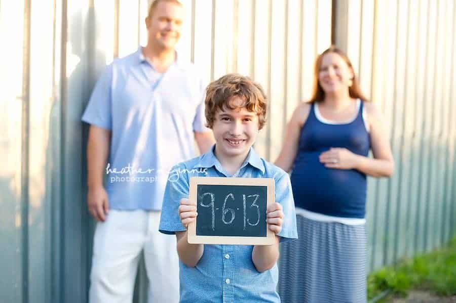 boy holding chalkboard in pregnancy announcement