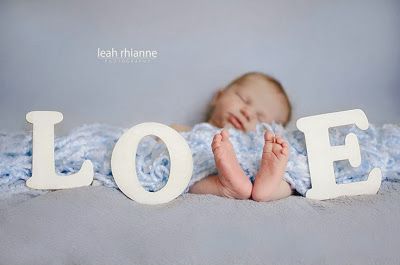 Baby laying on the floor with feet making the V in the word love