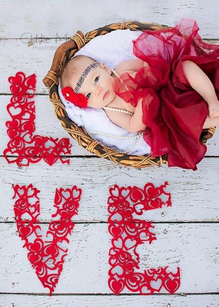 Baby laying in basket wearing red tutu with word Love spelled out