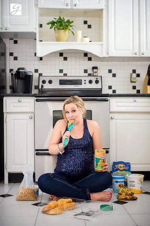 pregnant woman sitting on floor eating foods she craves for fun maternity photo