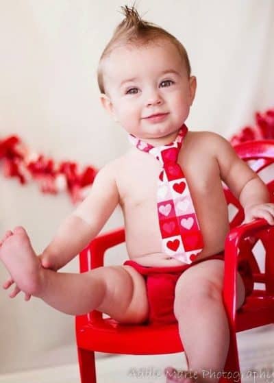Baby sitting in red chair with red, pink, and white heart tie ideas for Baby's First Valentine's Day Photo shoot