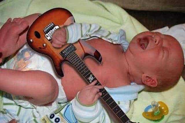 baby crying holding a guitar