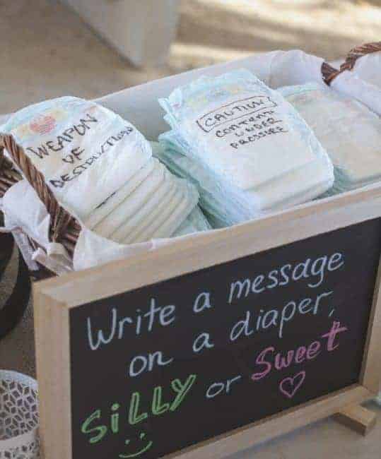 Basket full of diapers with funny and motivational messages written on them behind a sign that says "write a message on a diaper, silly or sweet"