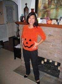 Woman dressed in an orange shirt made into a DIY pumpkin maternity costume