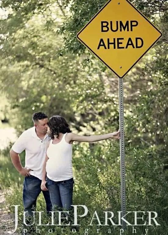 expecting couple kisses under bump ahead sign as a prop