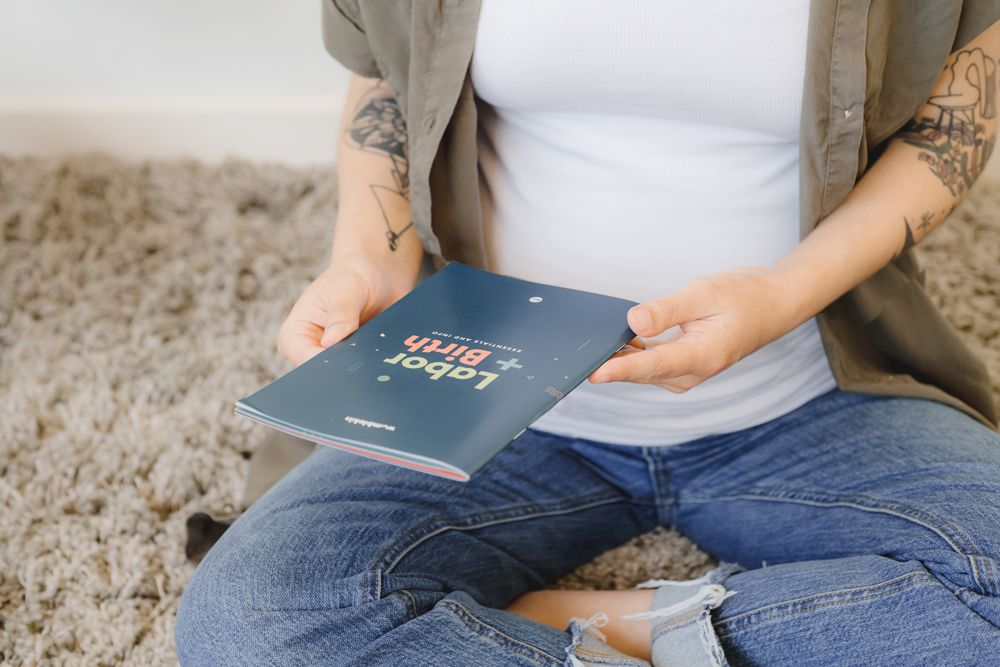 pregnant person holding labor and birth educational book