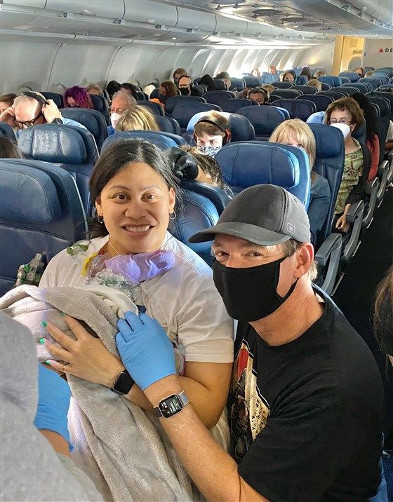 woman holding newborn baby after giving birth on a plane