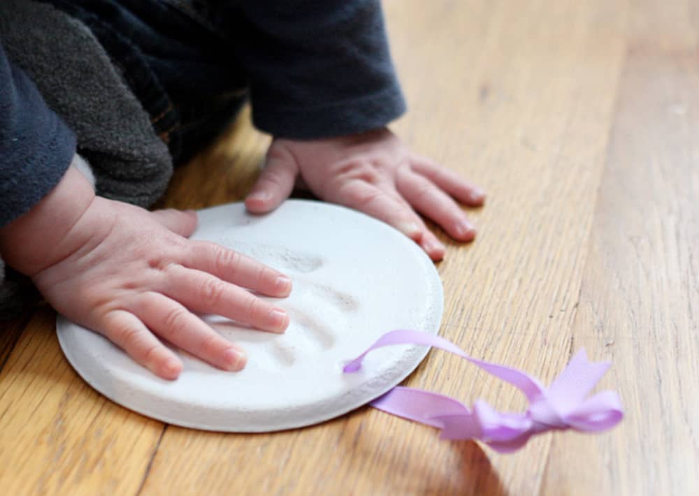 baby pressing hand into salt dough ornament