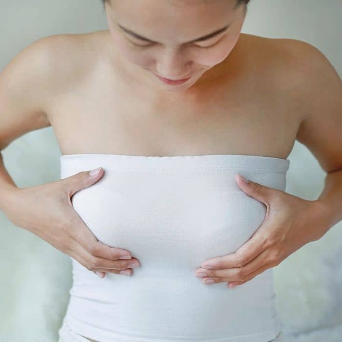 woman holding her breasts in a white tube top