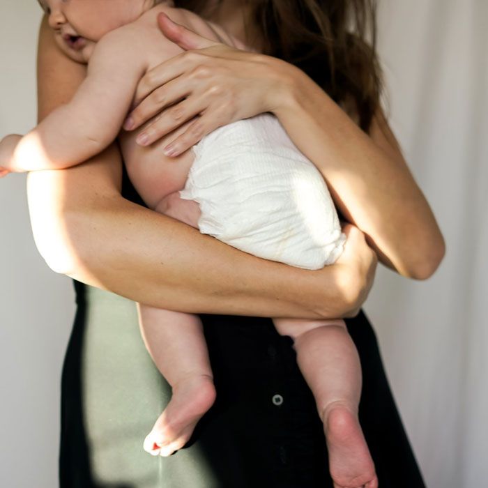 mom holding baby wearing disposable diaper from Coterie