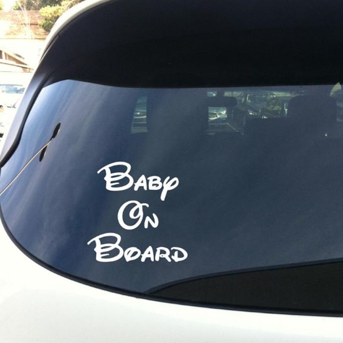 Rear windshield of car with decal that says "Baby on Board" in Disney script.