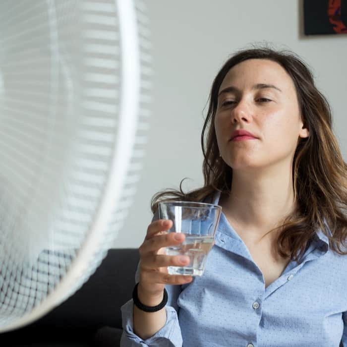 over heated woman drinking water due to early pregnancy symptoms