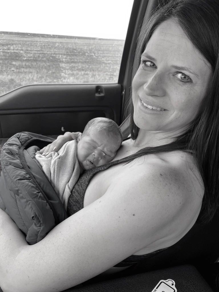 người phụ nữ ôm đứa con sơ sinh của mình sau khi sinh trong xe