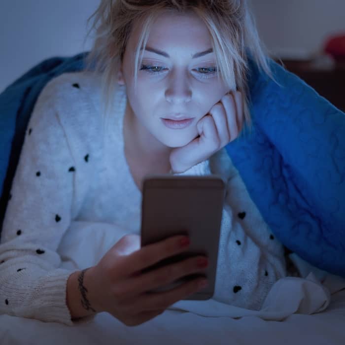 woman staring at her smartphone at night