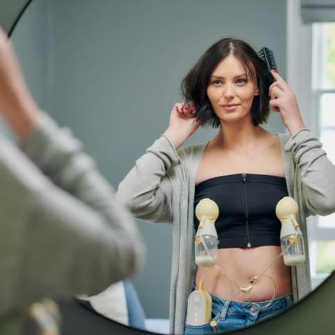 woman brushing her hair while pumping