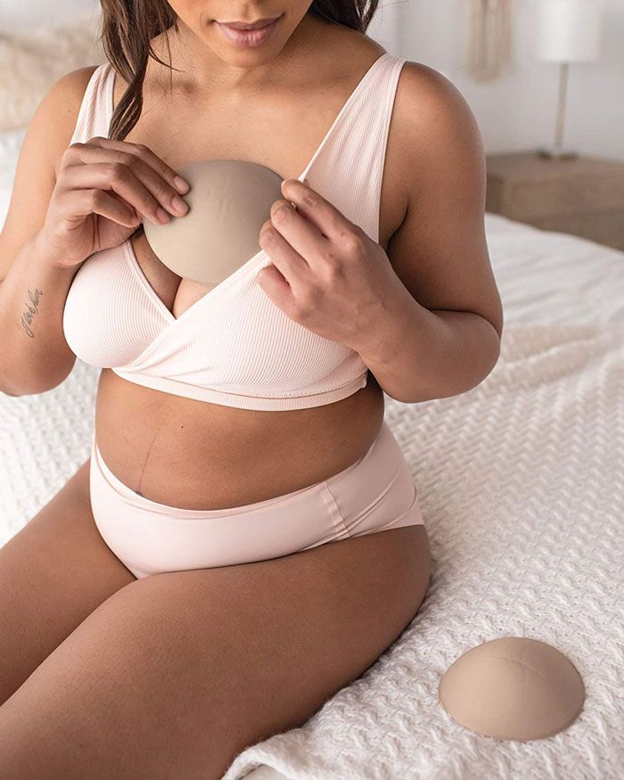 woman sitting on the bed using a kindred bravely reusable nursing pad