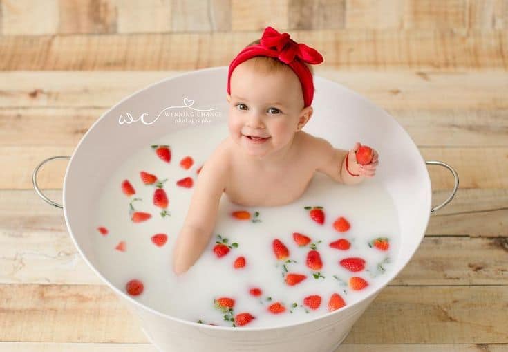 Baby in tub with milk bath and strawberries