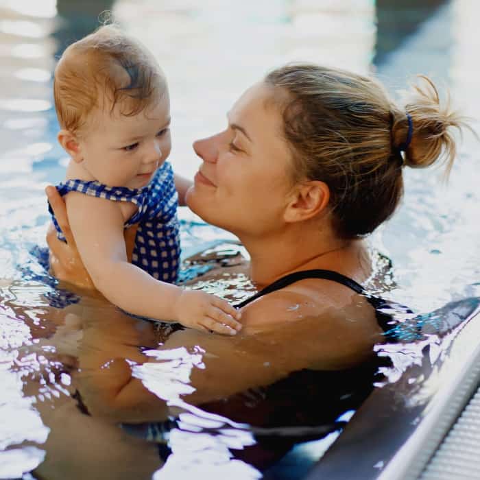 mom holding baby in pool