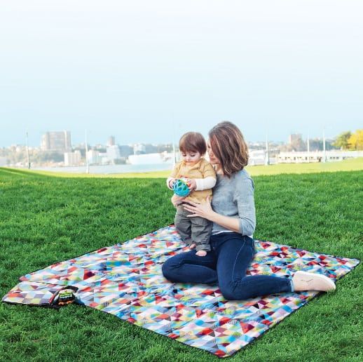 mom and baby sitting on beach blanket in the park