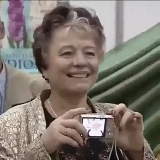 Gif of elderly woman using camera backwards and flashing it in her face