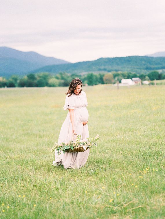 expecting mother holding a basket of flowers in a meadow