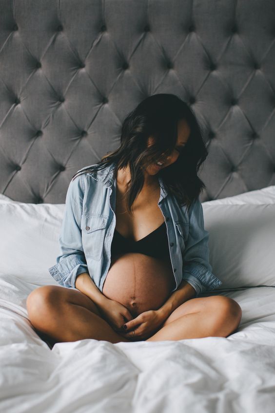 pregnant woman sitting on a bed maternity portrait