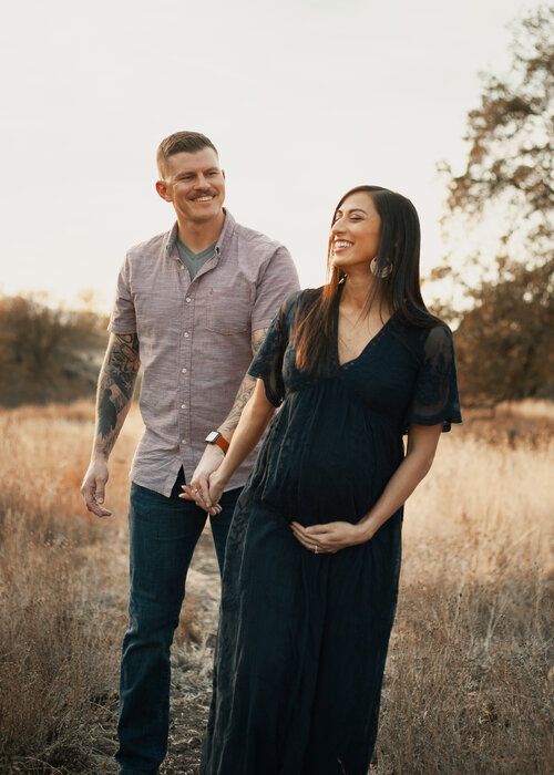 man and pregnant woman holding hands outdoors