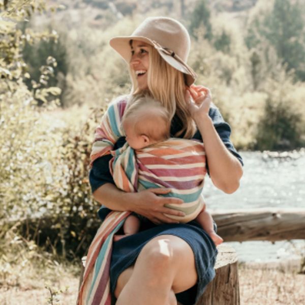 woman wearing her baby in a rainbow stripe hip baby carrier