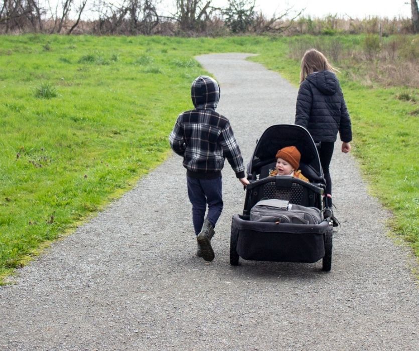 kids pulling veer wagon stroller with baby sitting in it