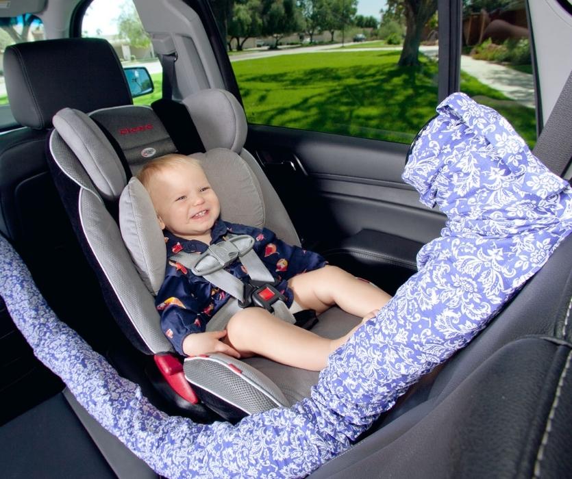 Interior of the car showing smiling baby sitting in car seat with Noggle positioned to blow cool air on them.