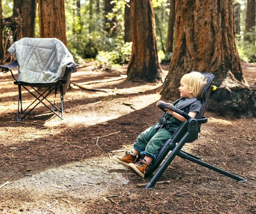 Photo of toddler strapped into the Switchback&Chill smiling while sitting in a forest.