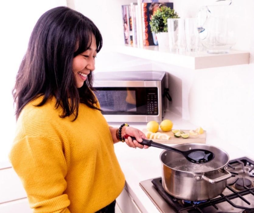 woman in kitchen using lucky iron fish in pot of water on the stove