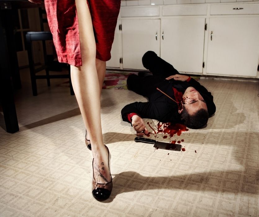 scene of a woman standing over a dead man on the floor