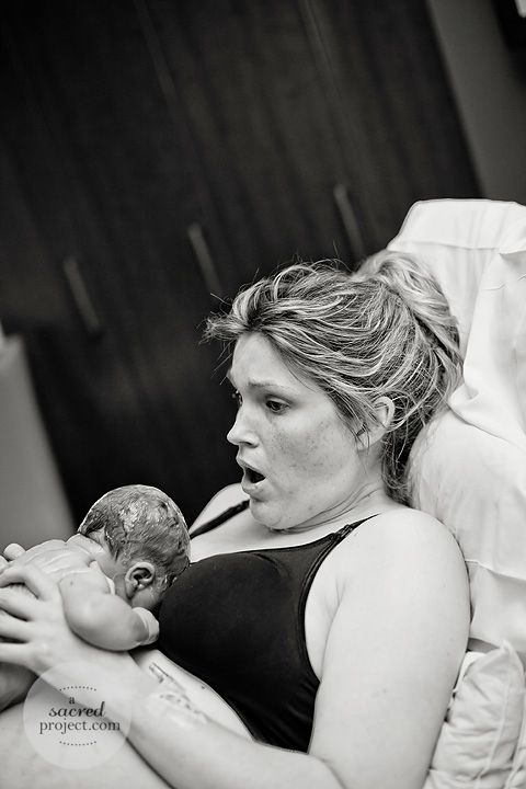 Black and white image of mom looking surprised as she holds her freshly born baby.