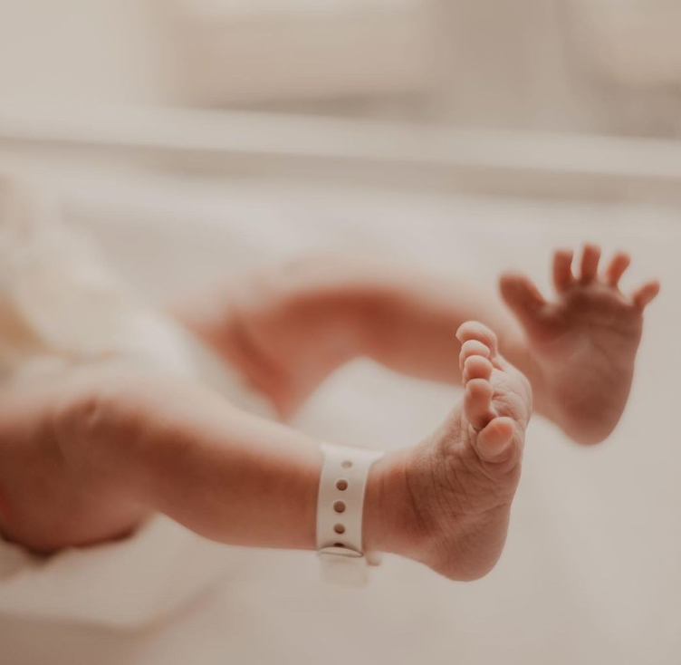 Close up color photo of wrinkly baby feet and hospital bracelet. 