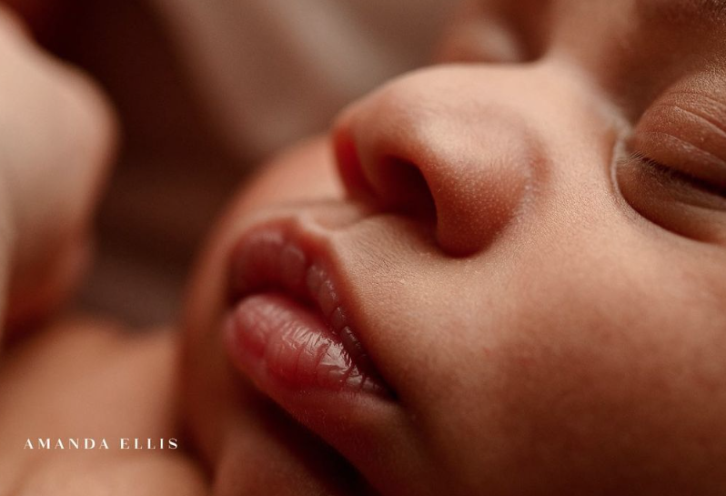 Color photo of a close up of baby's lips, nose, and closed eyes.