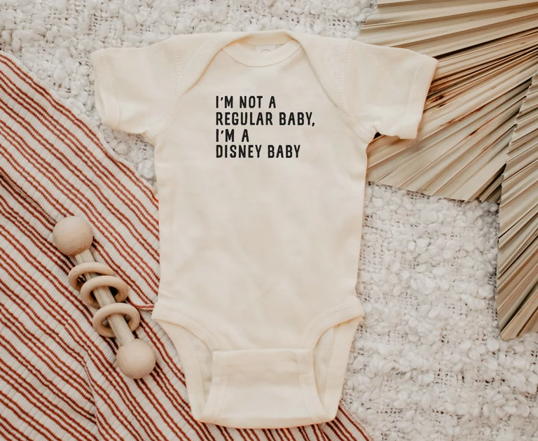 White onesie that says "I'm not like a regular baby I'm a Disney baby"