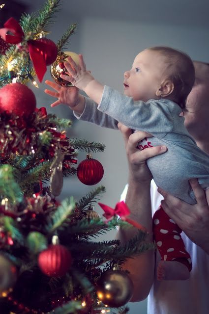 baby reaching for christmas ornament on tree