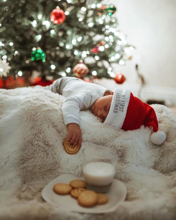 newborn baby holding cooking sleeping in front of christmas tree