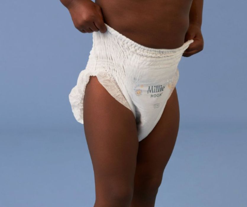 Toddler wearing only a diaper demonstrating how easy it is to pull up Millie Moon training pants