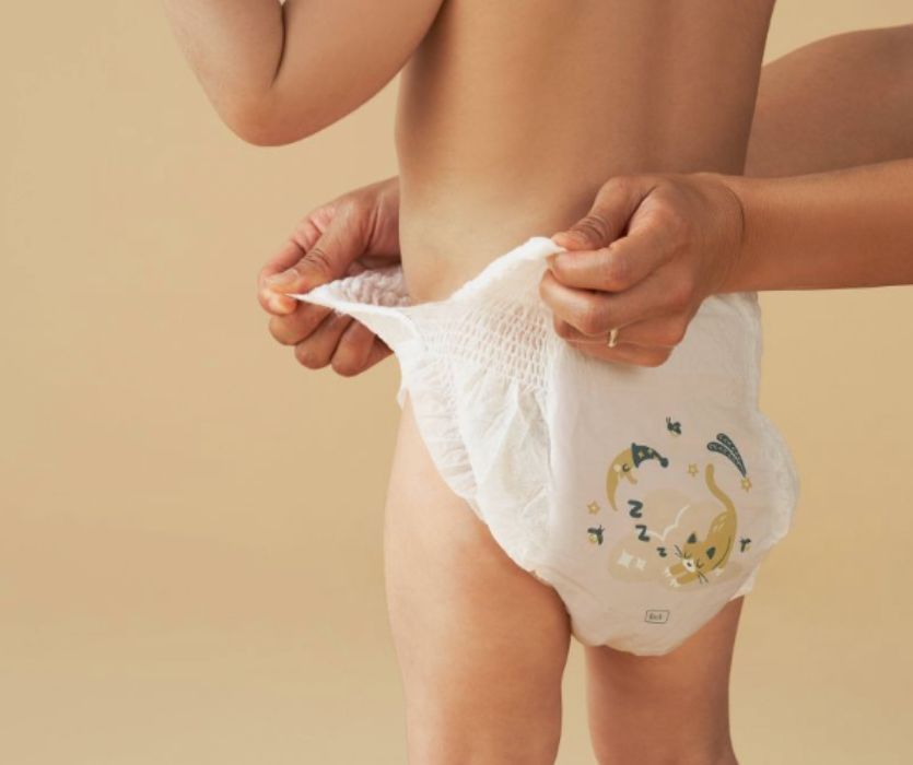 Photo of child wearing on Millie Moon training pant with care taker demonstrating how easy it is to tear the sides of the diaper.