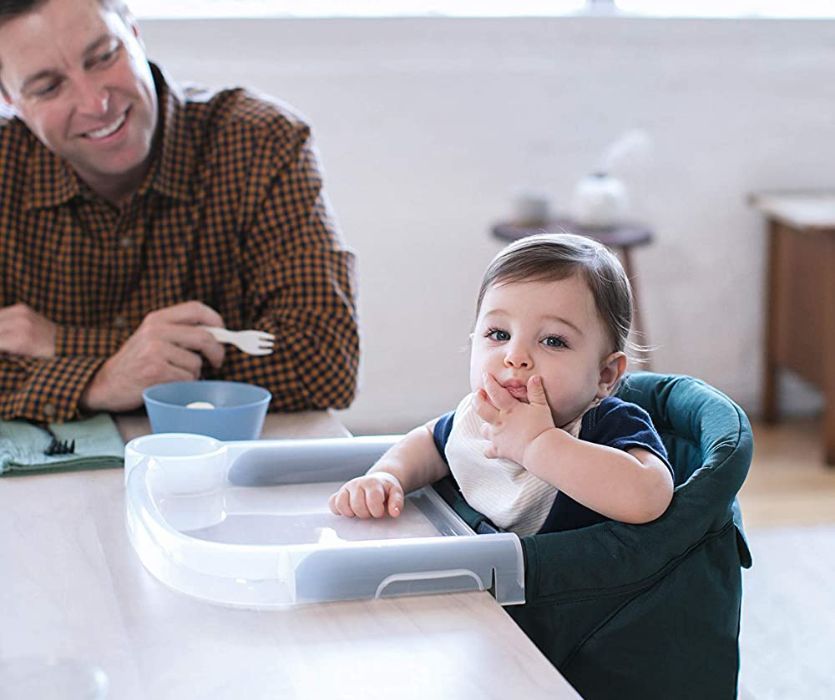 man smiling at baby in a portable highchair