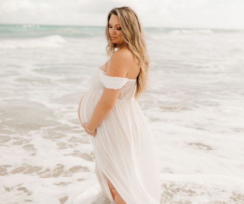 femme enceinte dans le surf avec une robe blanche