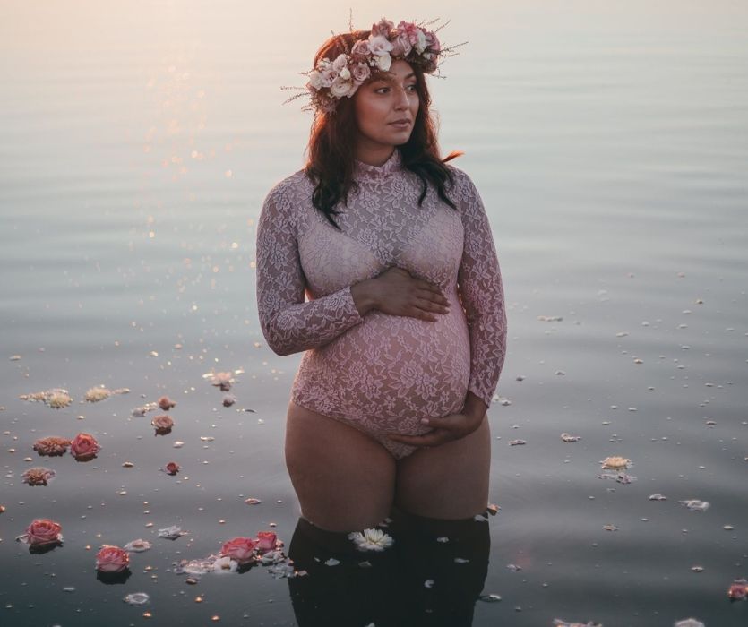 femme avec une couronne d'écoulement debout dans le lac tenant sa bosse de bébé