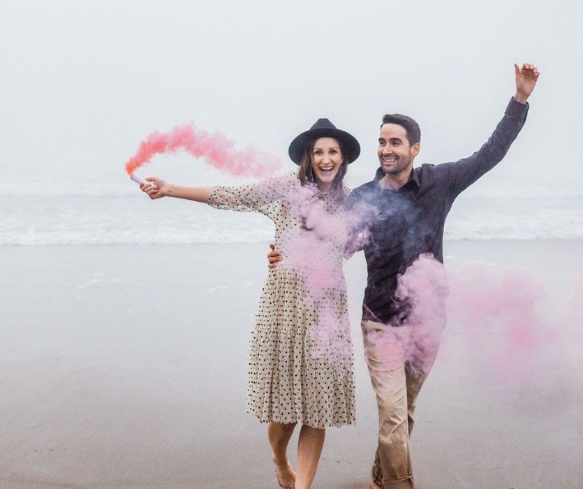 couple sur la plage avec une fusée éclairante de sexe rose