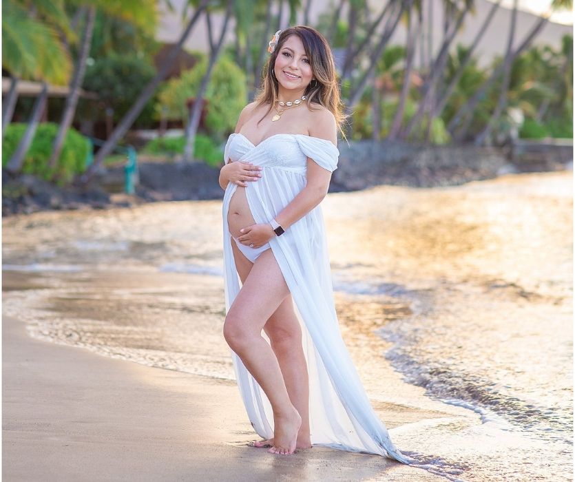 maternity shoot of a woman in the surf with a white dress