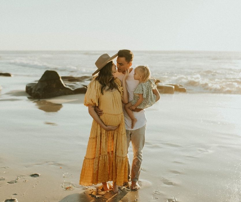 couple enceinte avec un tout-petit sur le point de s'embrasser sur la plage