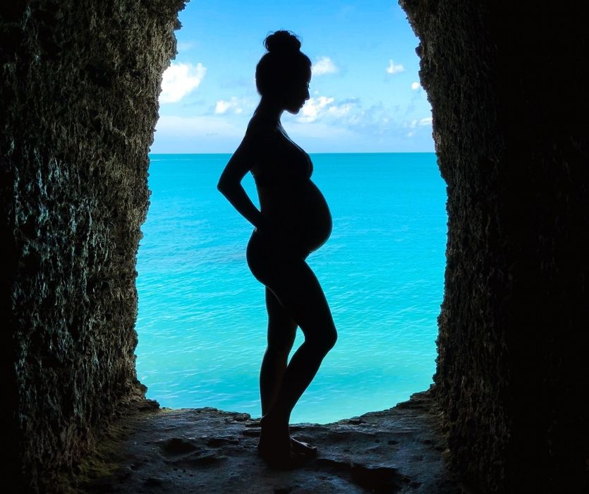 sihouette of pregnat woman with a tropical ocean in the background