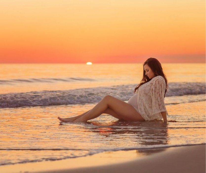 femme enceinte sur la plage au coucher du soleil