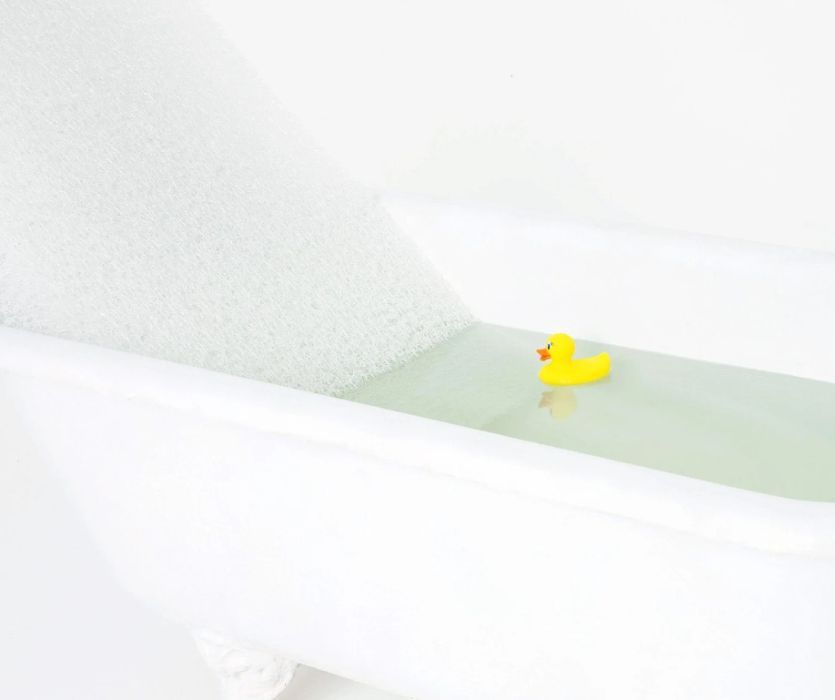 Newton Wovenaire Crib Mattress in bathtub with yellow rubber duck floating beside it